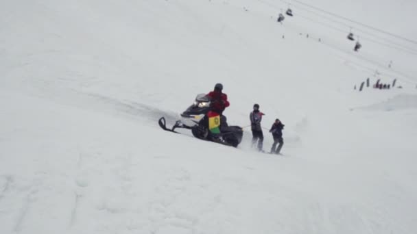 СОЧИ, РОССИЯ - 4 апреля 2016 года: Сноубордисты катаются на сноуборде, держа верёвку. Лыжный курорт. Экстремальное развлечение — стоковое видео