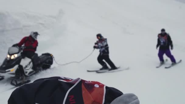 Sochi, Rusland - 4 April 2016: Skiër ritje op sneeuwscooter touw te houden. Afwerking. Skigebied. Extreme sporten. — Stockvideo