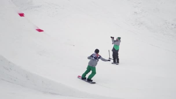 SOCHI, RUSIA - 4 DE ABRIL DE 2016: Salto snowboarder desde trampolín, coge snowboard en el aire. Estación de esquí. Paisaje . — Vídeos de Stock