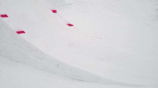 Sochi, Rusland - 4 April 2016: Snowboarder sprong van de Springplank, grab snowboard in lucht. Skigebied. Spiegelen. — Stockvideo