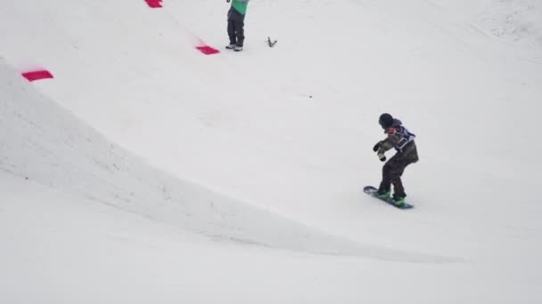 Sotschi, Russland - 4. April 2016: Snowboarder springen vom Sprungbrett, drehen sich in der Luft um, greifen zu. Skigebiet. Landschaft — Stockvideo