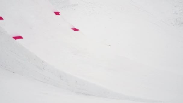 Sochi, Rusko - duben 4, 2016: Snowboardista skočit z můstku, chytni desky ve vzduchu. Lyžařské středisko. Zasněžené hory — Stock video