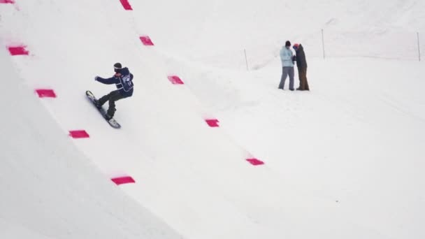 Sochi, Rusko - duben 4, 2016: Snowboardista skočit z můstku, aby překlopit ve vzduchu, chytit snowboardu. Lyžařské středisko — Stock video