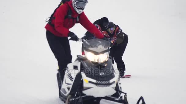 SOCHI, RUSIA - 4 DE ABRIL DE 2016: Los snowboarders viajan en la sujeción de la moto de nieve en la cuerda. Montañas. Truco peligroso. — Vídeos de Stock