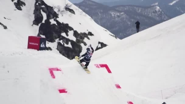 Sochi, Rusko - duben 4, 2016: Snowboardista jízdu na odrazový můstek, skok, aby překlopit ve vzduchu. Lyžařské středisko. Hory — Stock video