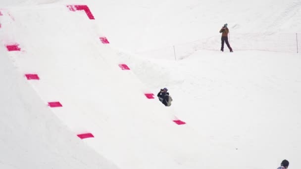 Sotschi, Russland - 4. April 2016: Snowboarder fahren auf dem Sprungbrett, machen Flip in der Luft, greifen. Berge. Kameramann. — Stockvideo