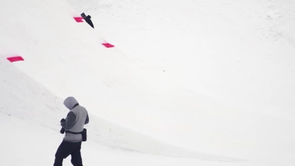 SOCHI, RUSIA - 4 DE ABRIL DE 2016: Paseo de esquiador en el trampolín hacer voltear en el aire con los pies cruzados. Montañas. Camarógrafo — Vídeo de stock