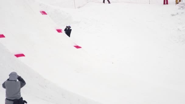 Sochi, Rusko - duben 4, 2016: Snowboardista jízdu na odrazový můstek, aby překlopit ve vzduchu. Zasněžená krajina — Stock video