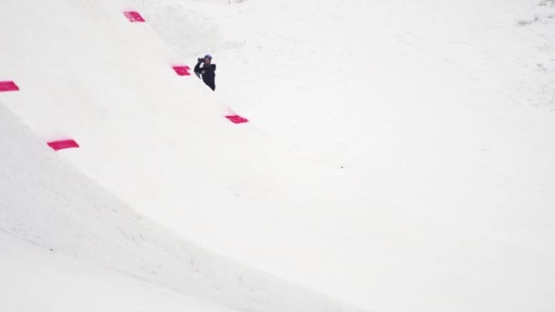 Sochi, Rusko - duben 4, 2016: Snowboardista jízdu na odrazový můstek, aby překlopit ve vzduchu. Zasněžené hory. Lidé — Stock video