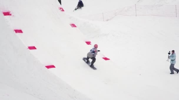 SOCHI, RÚSSIA - 4 de abril de 2016: Passeio de snowboarder no trampolim, faça salto mortal no ar. Montanhas nevadas. Desporto . — Vídeo de Stock