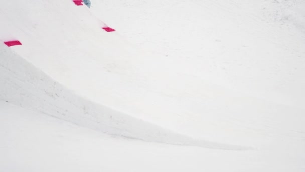 СОЧИ, РОССИЯ - 4 апреля 2016 года: Сноубордист прыгает с трамплина, делает трюк с изогнутыми ногами в воздухе. Горы — стоковое видео