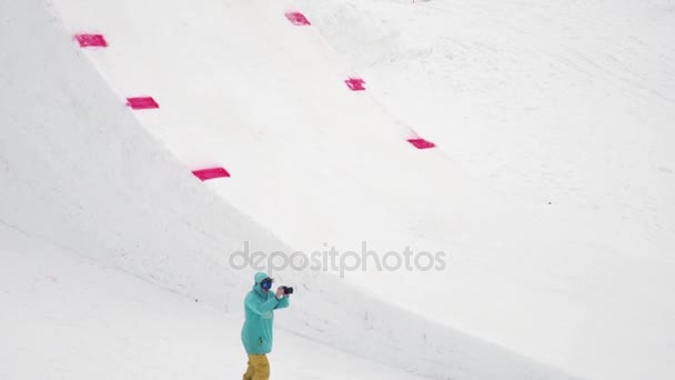 Sochi, Rusland - 4 April 2016: Cameraman schieten skiër rit op Springplank, maken flip in lucht. Besneeuwde bergen. — Stockvideo