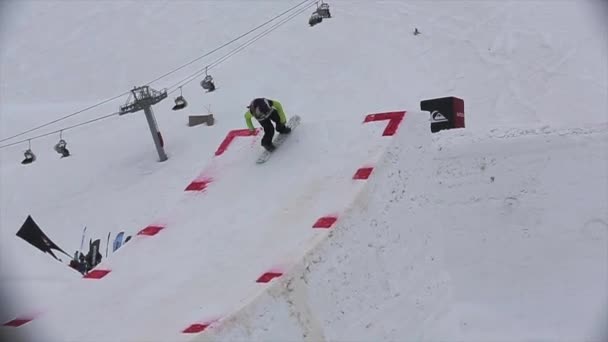Sochi, Rusland - 4 April 2016: Snowboarder sprong van de Springplank, maken spiegelen. Skigebied. Skilift. Cameraman. — Stockvideo