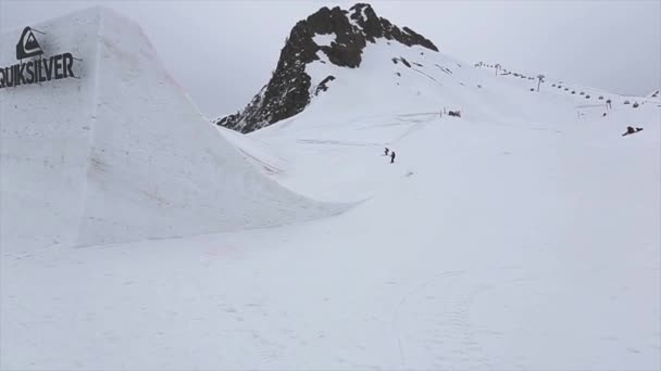 SOCHI, RUSSIA - 4 de abril de 2016: Snowboarder jump from springboard, make flip. Estância de esqui. Cameraman. Montanhas — Vídeo de Stock