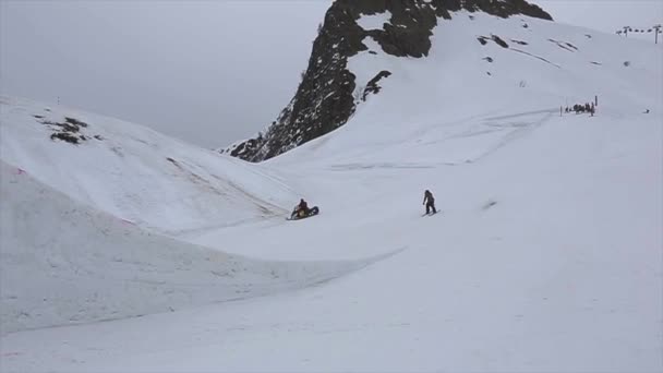 Sochi, Rusland - 4 April 2016: Skiër rit op Springplank. Sneeuwscooter. Grijze weer. Skigebied. Sport. Mensen — Stockvideo