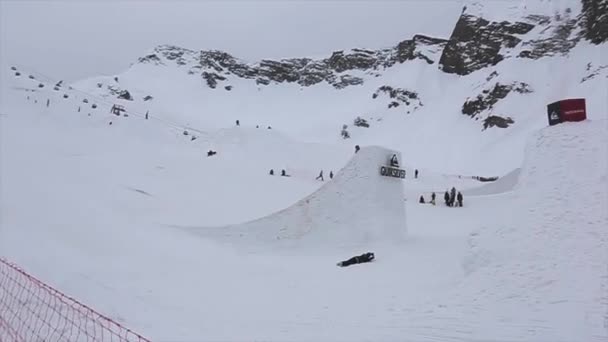 Sochi, Rusko - duben 4, 2016: Snowboardista skákat z vysokých odrazový můstek, ohnout nohy ve vzduchu. Lyžařské středisko. Hory — Stock video