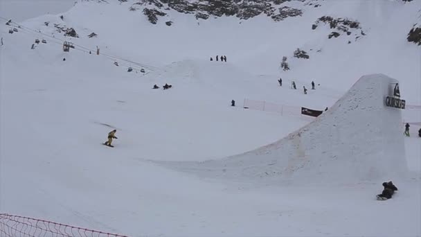 SOCHI, RUSIA - 4 DE ABRIL DE 2016: Snowboarder en traje amarillo salta desde un trampolín alto, haz flip. Estación de esquí . — Vídeo de stock