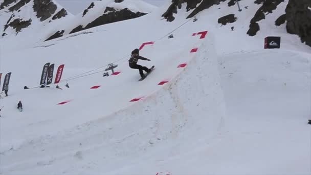 SOCHI, RUSSIE - 4 AVRIL 2016 : Le snowboardeur saute du tremplin haut, faire flip. Paysage de montagnes enneigées — Video