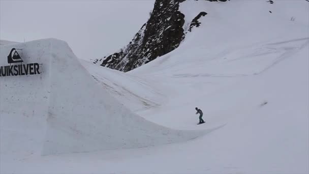 SOCHI, RUSSIA - 4 de abril de 2016: Snowboarder jump from high springboard on ski resort. Montanhas. Fazer salto mortal — Vídeo de Stock