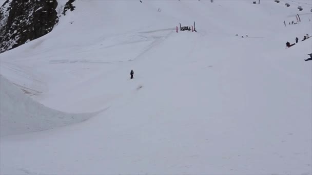 Sochi, Російська Федерація - 4 квітня 2016: Сноубордист стрибок від високого плацдарм на гірськолижному курорті. Гори. Зробити фліп. — стокове відео