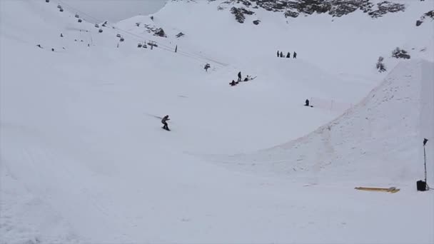 СОЧИ, РОССИЯ - 4 апреля 2016 года: Сноубордист прыгает с трамплина на горнолыжном курорте, делает флип. Горы . — стоковое видео