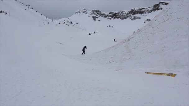 Σότσι, Ρωσία - 4 Απριλίου 2016: Άλμα Snowboarder από υψηλή εφαλτήριο για το χιονοδρομικό κέντρο. Βουνά. Γκρίζα καιρικές — Αρχείο Βίντεο