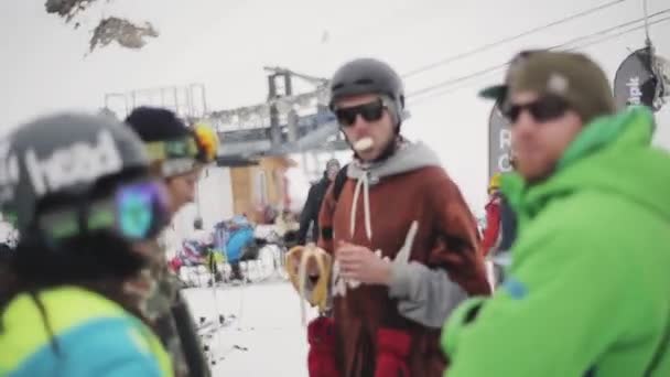 Σότσι, Ρωσία - 4 Απριλίου 2016: Snowboarders διαμονή στο κράνος, γυαλιά ηλίου σε encamp στο χιονοδρομικό κέντρο. Τρώει μπανάνα — Αρχείο Βίντεο
