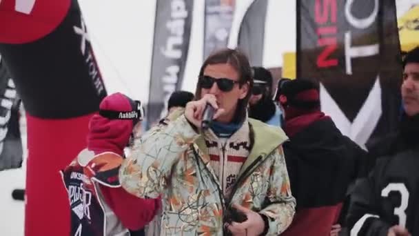 Sochi, Rusland - 4 April 2016: Host met microfoon zeggen woorden. Skiërs en snowboarders in encamp in skigebied. — Stockvideo