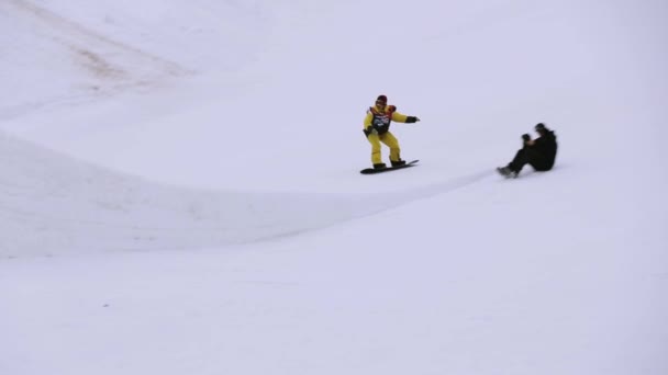 SOCHI, RÚSSIA - 4 de abril de 2016: Snowboarder jump from springboard on ski resort. Montanhas nevadas. Cameraman — Vídeo de Stock