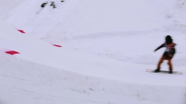 SOCHI, RUSIA - 4 DE ABRIL DE 2016: Salto snowboarder desde trampolín alto en estación de esquí. Paisaje. Clima gris — Vídeos de Stock