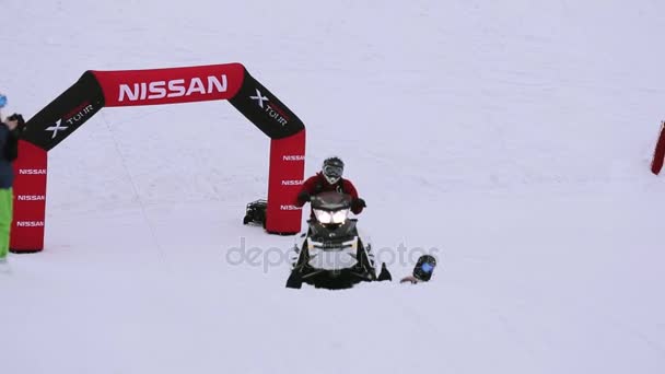 СОЧИ, РОССИЯ - 4 апреля 2016 года: Сноубордист и лыжник катаются на снегоходе, держа на веревке. Лыжный курорт. Снежный . — стоковое видео