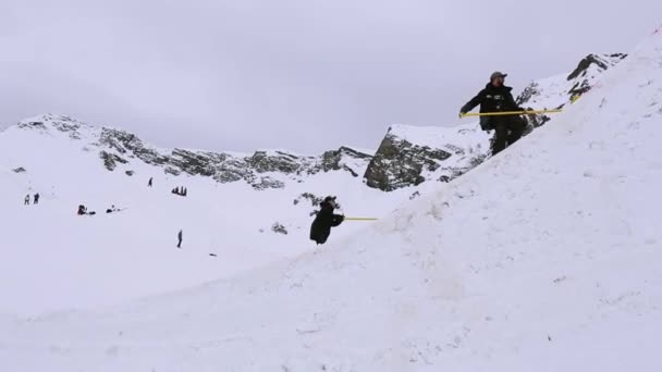 SOCHI, RÚSSIA - 4 de abril de 2016: Dois homens limpam trampolim em estância de esqui por pás. Paisagem de montanhas nevadas — Vídeo de Stock