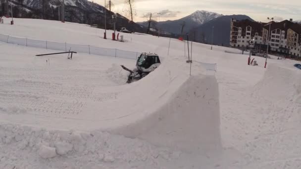 Sochi, Rusko - 1. dubna 2016: Quadrocopter natáčení rolba čerstvým sněhem na stopě. Lyžařské středisko. Lidé. Večer — Stock video