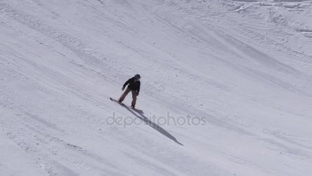 Sochi, Ryssland - April 1, 2016: Ski resort. Snowboardåkare rida från backen. Språngbrädor. Snötäckta berg. Soligt — Stockvideo