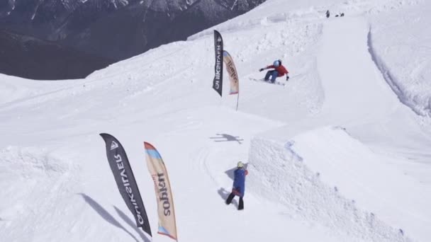 SOCHI, RUSIA - 1 DE ABRIL DE 2016: Estación de esquí. Esquiador salto de altura desde trampolín. Flexiona los pies. Montañas nevadas. Soleado. — Vídeo de stock