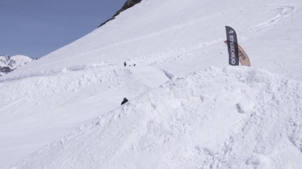 SOCHI, RUSSIA - APRIL 1, 2016: Ski resort. Snowboarder high jump from springboard. Slope. Snow mountains. Sunny — Stock Video