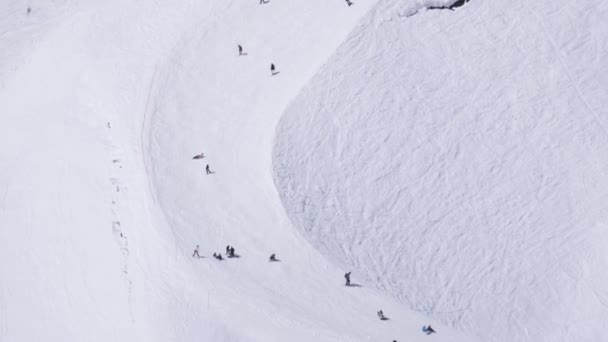 SOCHI, RUSIA - 1 DE ABRIL DE 2016: Estación de esquí. Snowboarders y esquiadores cabalgan desde las pistas. Encamp. Trampolín. Sol — Vídeo de stock