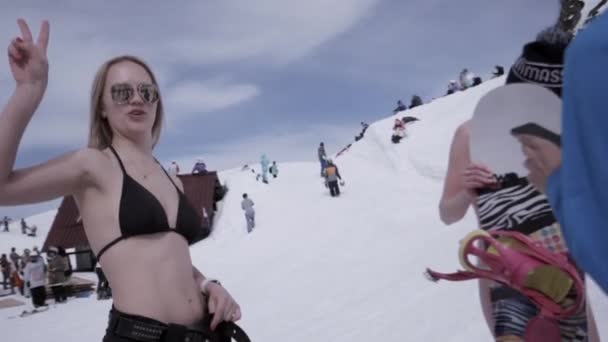 Soczi, Rosja - 1 kwietnia 2016: Ośrodek narciarski. Dziewczyna w czarnym bikini uśmiech w aparacie. Ludzie w encamp. Narciarzy. Słońce — Wideo stockowe