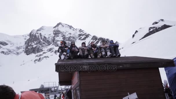 Sochi, Rusland - 1 April 2016: Skiresort. Snowboarders zittend op dak van huis in encamp. Skiërs. Bergen — Stockvideo