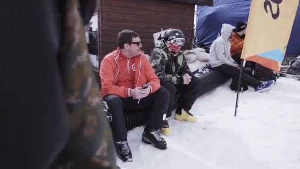Sochi, Російська Федерація - 1 квітня 2016: Гірськолижний курорт. Енкамп сноубордисти, сидячи на даху будинку в. Люди. Гори — стокове відео