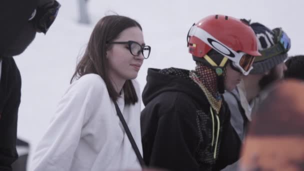 SOCHI, RUSIA - 1 DE ABRIL DE 2016: Estación de esquí. Chica joven en gafas entre snowboarders y esquiadores en el campamento . — Vídeos de Stock