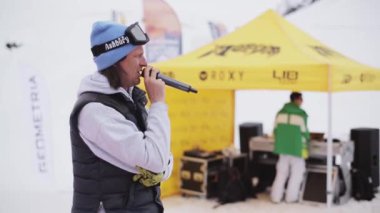 Soçi, Rusya - 6 Nisan 2016: Adam mikrofon snowboard ve kayak kayakçı arasında. Sarı çadır