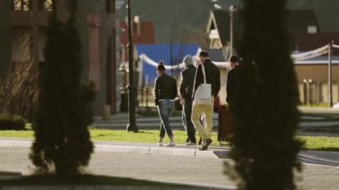 Sochi, Rusya Federasyonu - 8 Nisan 2016: Bir grup genç insan yavaş yavaş sokakta yürümek. Güneşli akşam. Çam ağaçları.