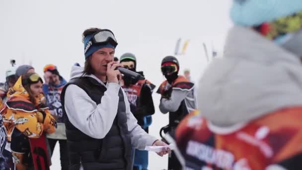 SOCHI, RUSIA - 6 DE ABRIL DE 2016: El hombre con micrófono dice entre los snowboarders y esquiadores en la estación de esquí. Concurso — Vídeos de Stock