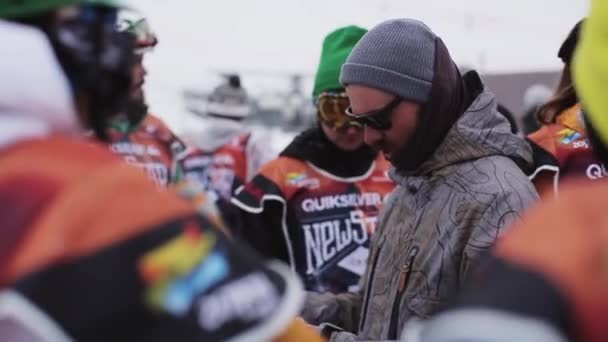 СОЧИ, РОССИЯ - 6 апреля 2016 года: Бородатый мужчина в солнечных очках разговаривает со сноубордистами и лыжниками на горнолыжном курорте . — стоковое видео