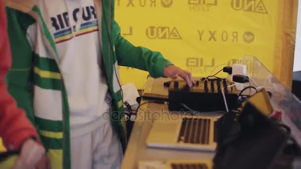 SOCHI, RUSIA - 6 DE ABRIL DE 2016: Dj mezclando en tienda amarilla en la fiesta en la estación de esquí. Sonríe. Vacaciones. Laptop. Baile — Vídeos de Stock