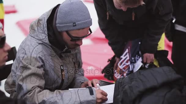 Sochi, Rusko - 6. dubna 2016: Muž zápis seznam účastníků v soutěži v lyžařském středisku. Snowboardisty a lyžaře — Stock video