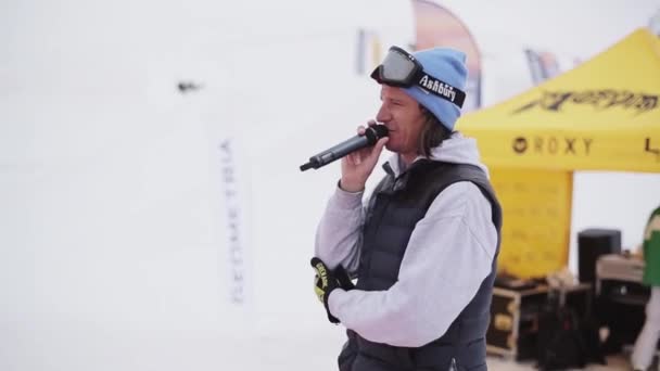 Sochi, Rusland - 6 April 2016: Man met microfoon zeggen onder snowboarders en skiërs op ski-oord. Sneeuw — Stockvideo