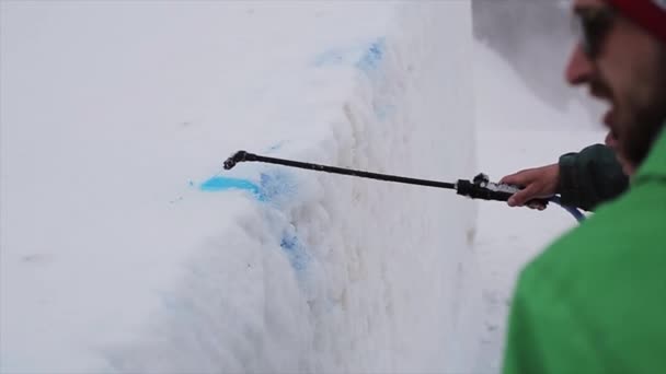 Sochi, Rusko - 6. dubna 2016: Dva muži spay modré barvivo na zasněženém svahu na lyžařské středisko. Hory. Označení. Sportovní — Stock video