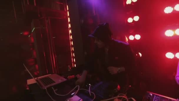 Soczi, Rosja - 8 kwietnia 2016: Dj w kapturem rotująca gramofon na party w klubie nocnym. Taniec. Czerwone reflektory — Wideo stockowe
